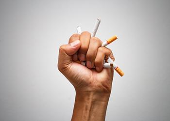 A hand crushing multiple cigarettes