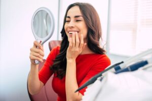 Smiling dental patient holding hand mirror